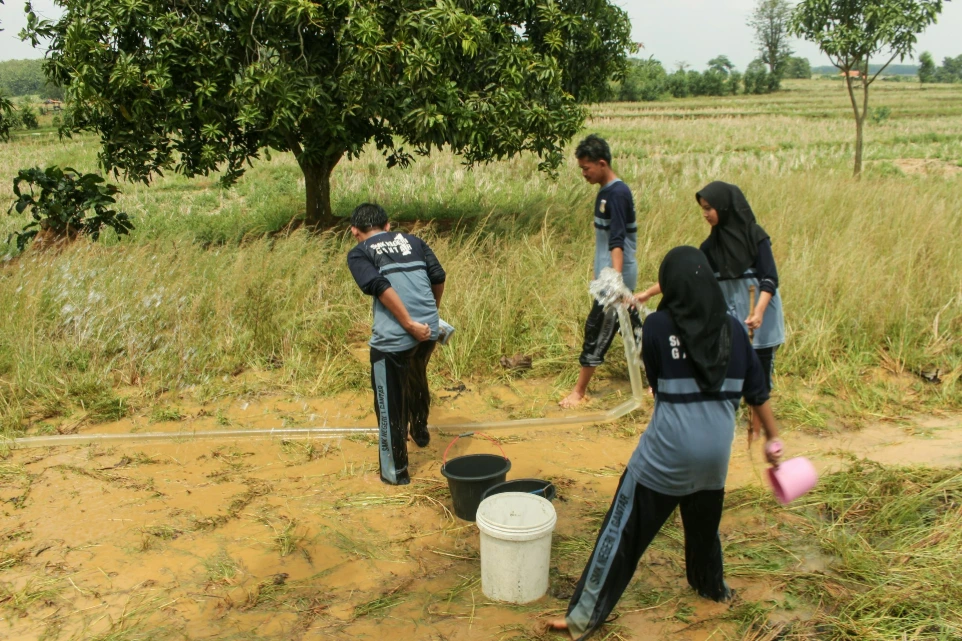 Students collecting water from a well in a rural area.